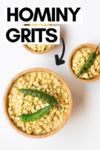 one large bowl and two small bowls of hominy grits topped with grilled serrano peppers and a text overlay that reads "hominy grits" with an arrow pointing toward the big bowl